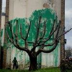Banksy adorns bare tree with green leaves