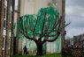 Banksy adorns bare tree with green leaves